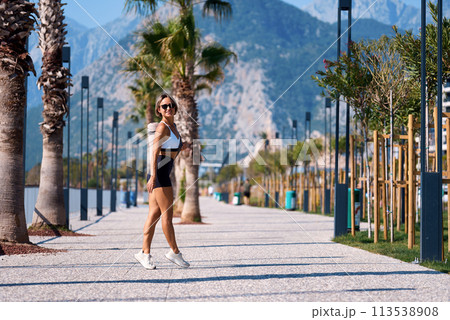 fit girl in sportswear goes to morning workout at park, carrying yoga mat holds bottle of water fit girl in sportswear goes to morning workout at park, carrying yoga mat holds bottle of water 113538908