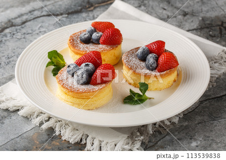 Japanese soft pancakes with strawberry and blueberries sprinkled with powdered sugar close-up on a plate. Horizontal 113539838