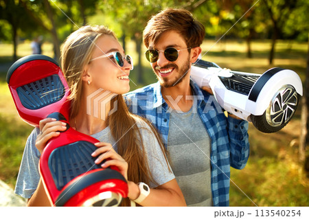 Young man and woman riding on the Hoverboard in the park. content technologies. a new movement. 113540254