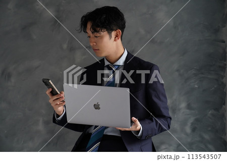 パソコンを持って仕事をするスーツ姿の若い男性 113543507