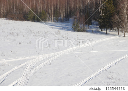 Deserted winter landscape. A path of footprints stretches across the pure white snow 113544358
