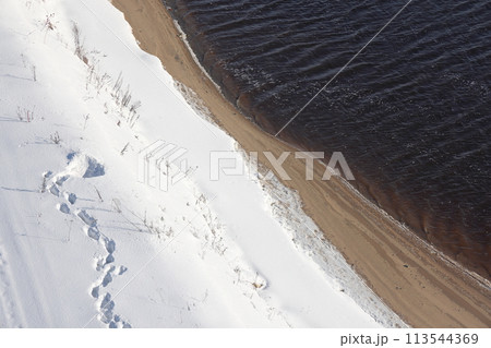 Deserted winter landscape. A path of footprints stretches across the pure white snow. Deserted winter landscape. A path of footprints stretches across the pure white snow. 113544369