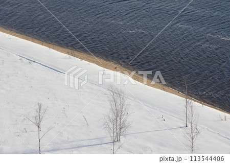 Deserted winter landscape. A path of footprints stretches across the pure white snow 113544406