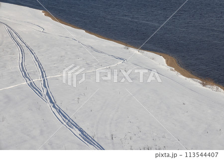 Deserted winter landscape. A path of footprints stretches across the pure white snow 113544407