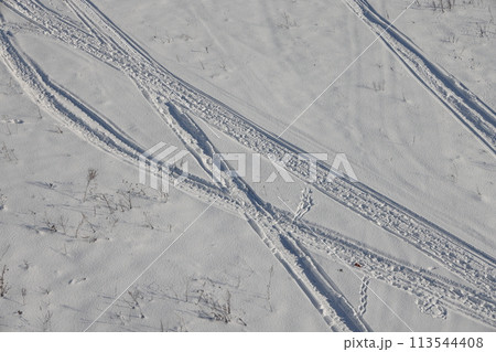 Deserted winter landscape. A path of footprints stretches across the pure white snow 113544408