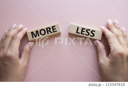 More or Less symbol. Concept word More or Less on wooden blocks. Businessman hand. Beautiful pink background. Business and More or Less concept. Copy space More or Less symbol. Concept word More or Less on wooden blocks. Businessman hand. Beautiful pink background. Business and More or Less concept. Copy space 113547610