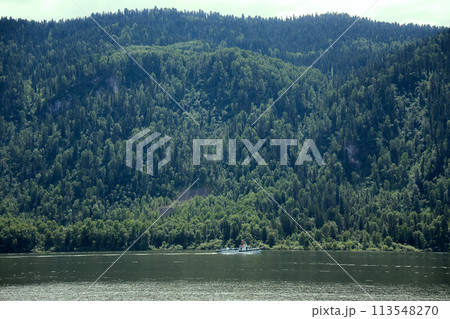 boat goes along the shore of a mountain lake 113548270