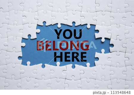 You belong here symbol. White puzzle with words You belong here. Beautiful blue background. Business and You belong here concept. Copy space. 113548648