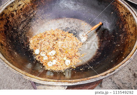 Appetizing traditional Uzbek pilaf in a large cauldron Appetizing traditional Uzbek pilaf in a large cauldron 113549292