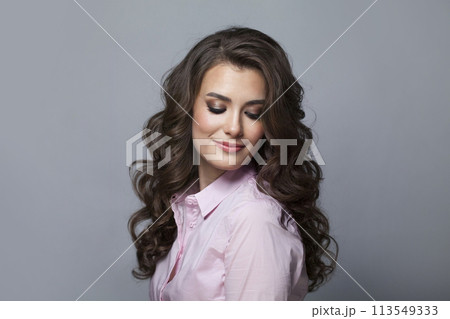 Glorious woman with long healthy wavy hair, cute smile and make-up looking at camera  113549333