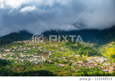 Traditional terrace village Sao Vicente, Madeira Island, Portugal. Small houses and gardens among a green mountain landscape in stormy weather. 113549553