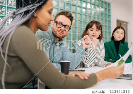 Closeup of African female leader with business group talking at meeting table in contemporary office, discussing project, sharing ideas, brainstorming, speaking. Creative team discussing new ideas 113551816