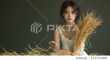 暗い背景の前で真剣な表情で稲穂を持つ女性 113552066
