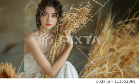 稲穂を持って正面を見つめる若い女性 113552069
