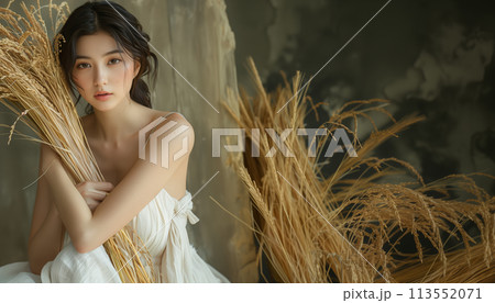 稲穂を抱いてこちらを見つめる若い女性 113552071