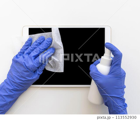 person disinfecting a tablet 113552930