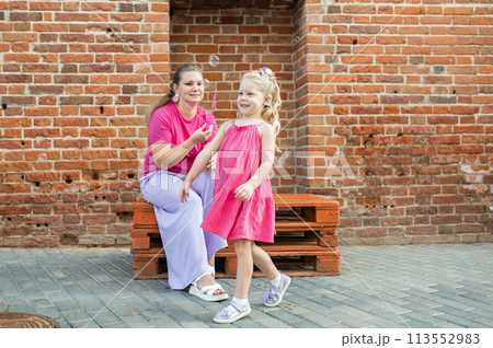 Mother holds and have fun her child with hearing aids and cochlear implants summer outdoor . Deaf and health concept. Diversity and inclusion. Copy space 113552983