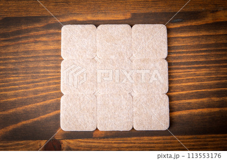 Furniture Protection Felt on a dark wood texture background 113553176