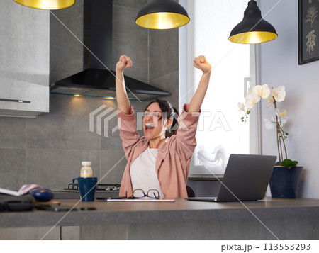 young woman with laptop computer working at home office and celebrating success 113553293