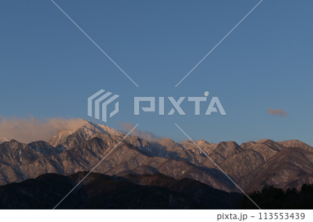 月齢16.2朝焼けの南アルプスの山並みに掛かる立待月 113553439