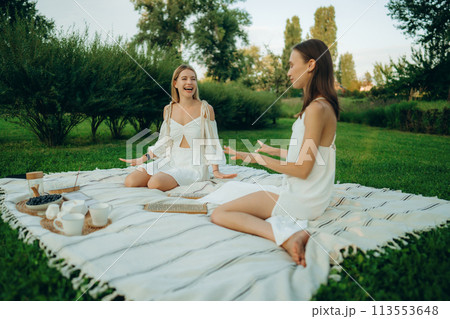 Two young women meditate and do yoga in nature. Two young women meditate and do yoga in nature. 113553648