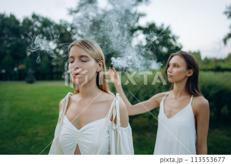 A young woman practices meditation in nature. Meditation with smoke. A young woman practices meditation in nature. Meditation with smoke. 113553677