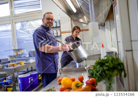 Colleagues cooking in the kitchen and looking busy Colleagues cooking in the kitchen and looking busy 113554166