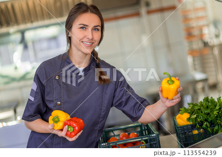 Young smiling woman with peppers in hands in the kitchen 113554239
