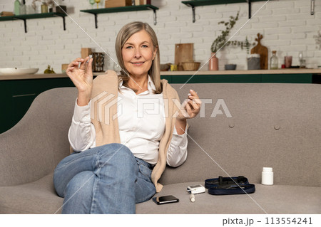 Good-looking diabetic woman with insulin syringe sitting on the sofa at home 113554241