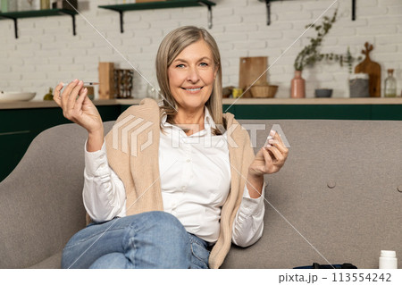 Good-looking diabetic woman with insulin syringe sitting on the sofa at home 113554242