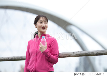 ペットボトルの水を持つスポーツウエアのミドル女性 113556033