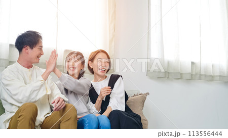 リビングルームでテレビを見ながら喜ぶ親子 113556444