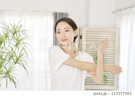 自宅で腕のストレッチをする40代の女性 113557565