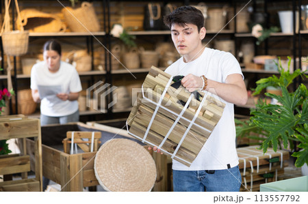 Guy looking for folded wooden garden furniture in store 113557792