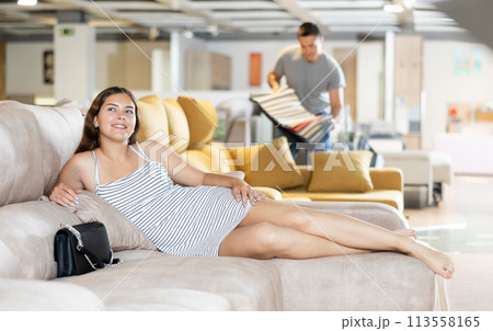 Smiling girl lying on sofa dreaming about buying in furniture store 113558165