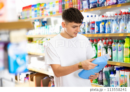 Focused young guy buying household chemicals in supermarket Focused young guy buying household chemicals in supermarket 113558241