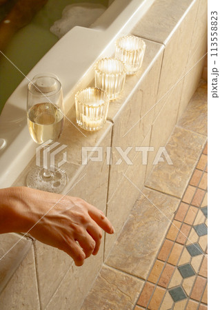 Woman Relaxing in the Bathroom Spa Tub with a Glass of Sparkling Champagne and Candles. Woman Relaxing in the Bathroom Spa Tub with a Glass of Sparkling Champagne and Candles. 113558823