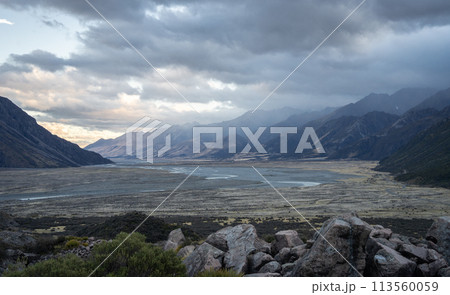Vast alpine valley with mountain ranges during sunset and storm approaching, New Zealand Vast alpine valley with mountain ranges during sunset and storm approaching, New Zealand 113560059