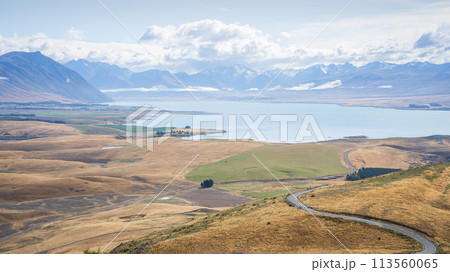 Autumnal landscape scenery with turquoise alpine lake, orange rolling hills and snowy mountains  113560065