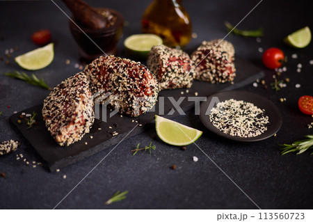 piece of tuna fillet covered with sesame seeds on a stone serving board before cooking piece of tuna fillet covered with sesame seeds on a stone serving board before cooking 113560723