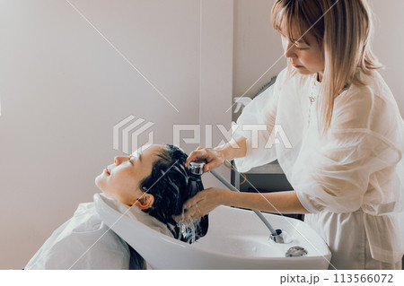 美容室でシャンプーをしてもらう若い女性 美容室でシャンプーをしてもらう若い女性 113566072