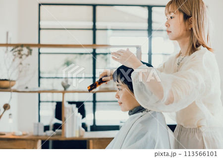 美容室でカットをしてもらう若い女性 美容室でカットをしてもらう若い女性 113566101