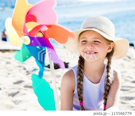 Girl with windmill on sea in summer 113566779