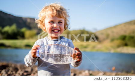 Poor, beggar, hungry smiling child eager to drink water from a plastic bottle. 113568320