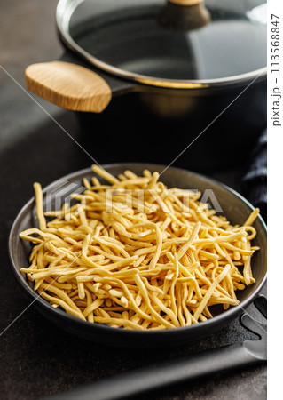 Uncooked spaetzle pasta on plate on kitchen table. Uncooked spaetzle pasta on plate on kitchen table. 113568847