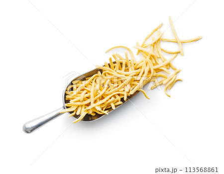 Uncooked spaetzle pasta in scoop isolated on white background. Uncooked spaetzle pasta in scoop isolated on white background. 113568861