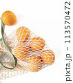 Fresh unpeeled oranges placed in reusable white mesh bag 113570472