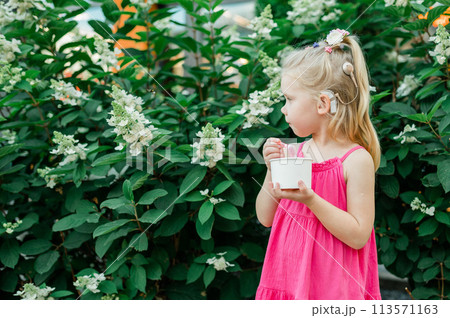 Child walks with cochlear implant hearing aid in summer street. Inclusion and modern technologies for treating hearing loss. Copy space 113571163