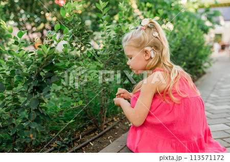 Child walks with cochlear implant hearing aid in summer street. Inclusion and modern technologies for treating hearing loss. Copy space 113571172