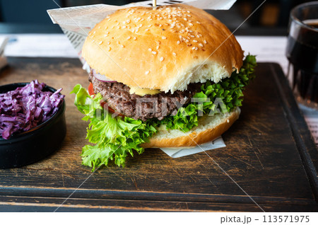 Classic hamburger with lettuce on a wooden plate, Belgium Classic hamburger with lettuce on a wooden plate, Belgium 113571975